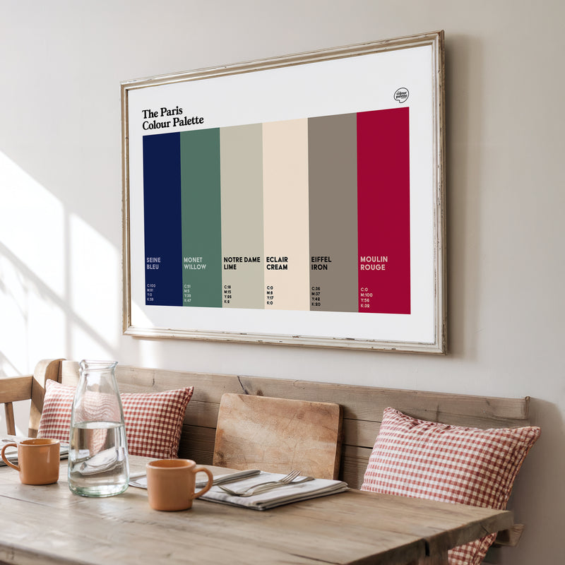 Framed Paris Colour Palette poster above a wooden table with a bench and cushions.